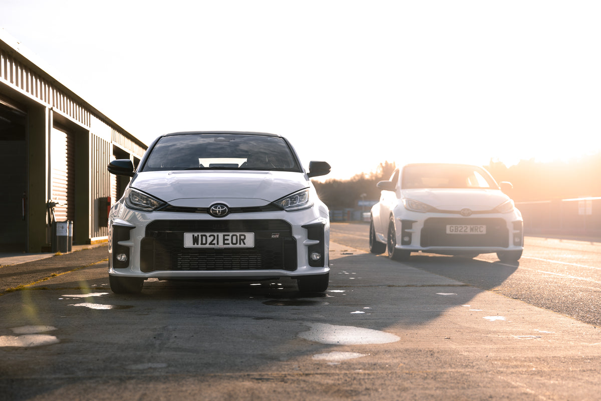 Two white Toyota cars on a road with a sunset in the background